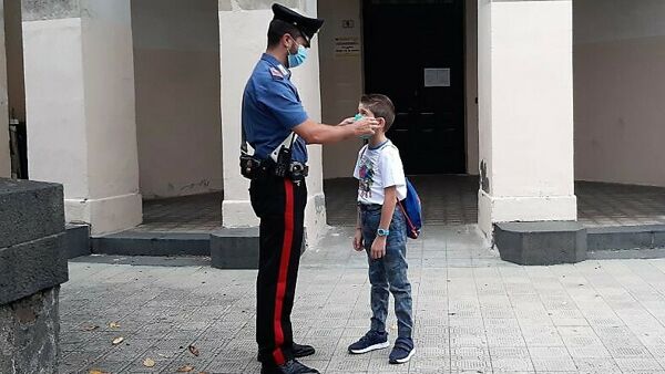 Un Carabiniere di fronte ad un bambino che va a scuola