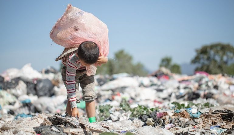 Un bambino che fruga fra i rifiuti di una discarica