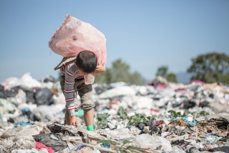 Un bambino che fruga fra i rifiuti di una discarica